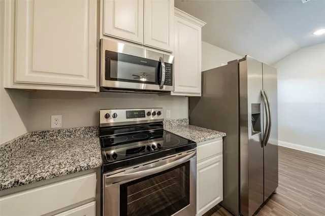 a kitchen with stainless steel appliances granite countertop a refrigerator stove and microwave