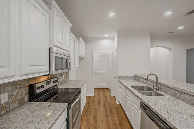 a kitchen with granite countertop a sink dishwasher stove and oven