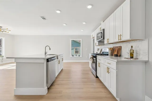 a large white kitchen with wooden floors and white stainless steel appliances