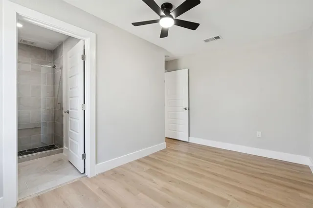 a view of kitchen with stainless steel appliances granite countertop a stove a sink a refrigerator and white cabinets with wooden floor