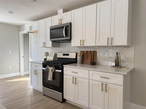 a view of kitchen with stainless steel appliances refrigerator stove microwave and cabinets