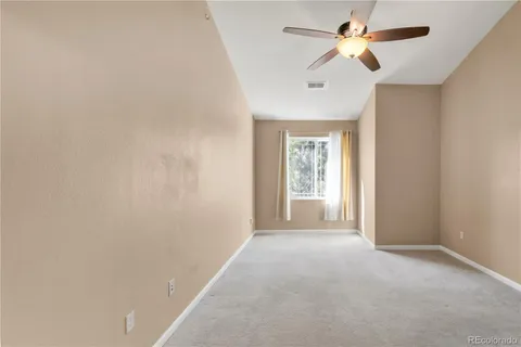 a view of a big room with a chandelier fan and windows