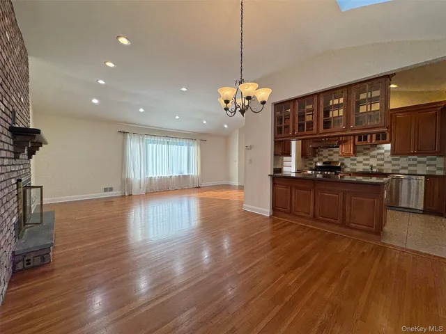 a large kitchen with stainless steel appliances granite countertop a stove and a wooden floors