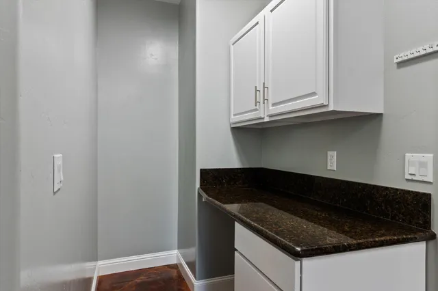 a kitchen with granite countertop white cabinets and a stove