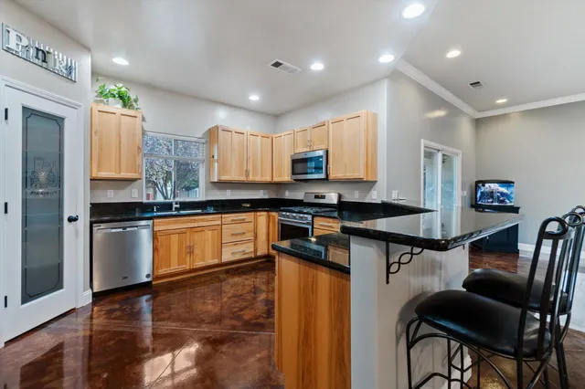 a kitchen with granite countertop a stove top oven a sink dishwasher a dining table and chairs
