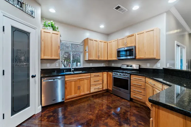 a kitchen with stainless steel appliances granite countertop a stove a sink and a microwave
