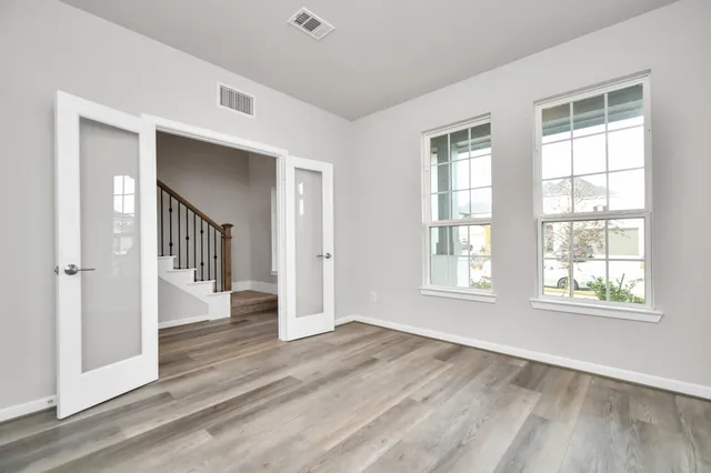 an empty room with wooden floor cabinet and windows