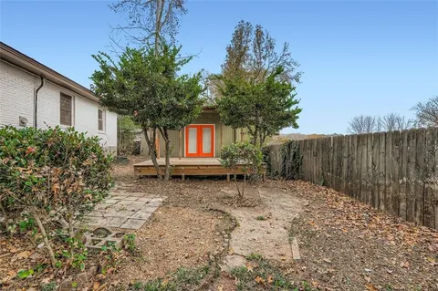 a backyard of a house with barbeque oven and trees