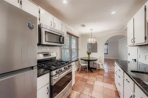 a kitchen with stainless steel appliances a stove a sink cabinets and a microwave