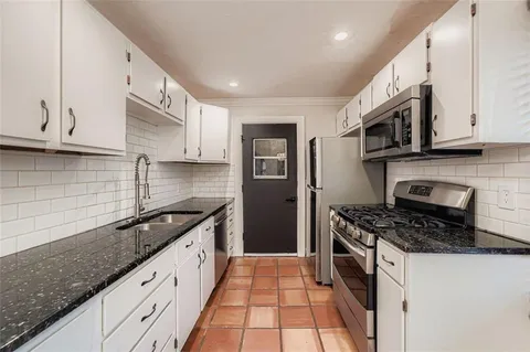 a kitchen with stainless steel appliances granite countertop a stove a sink and a microwave