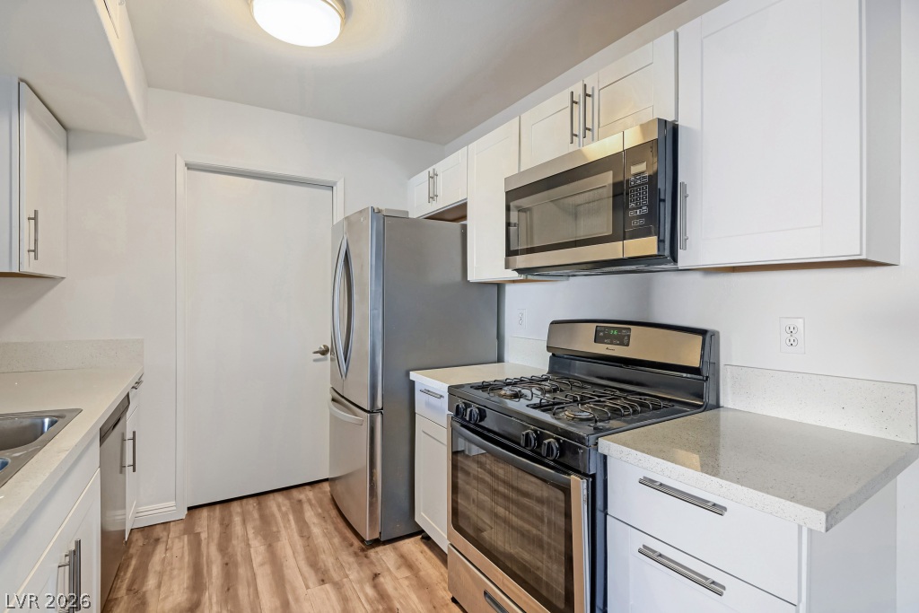 7885 West Flamingo Road, Unit 1003 Las Vegas, NV 89147 - Photo 11 of 22 Crisp white cabinetry pairs perfectly with modern stone countertops and rich wood-toned flooring.