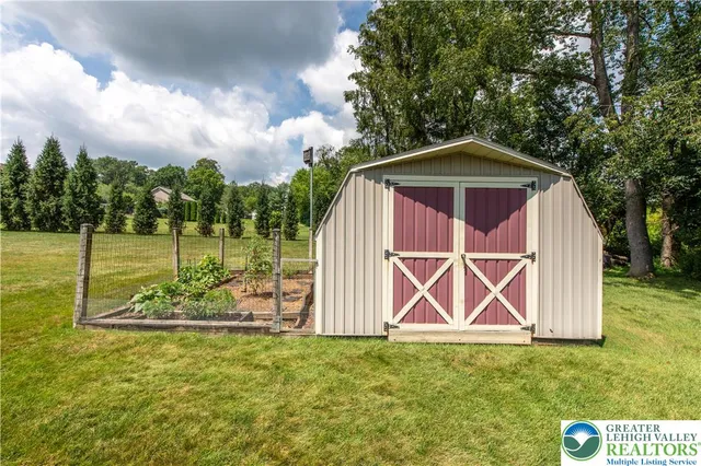 a view of a wooden house with a yard and wooden fence