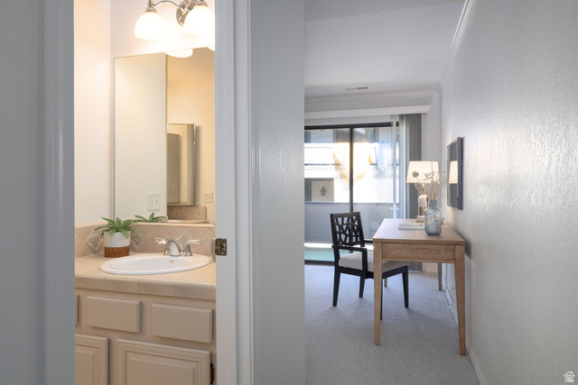 6936 South 775 East, Unit B Midvale, UT 84047 - Photo 12 of 33 Bathroom with vanity, a textured wall, crown molding, light carpet, and tasteful backsplash