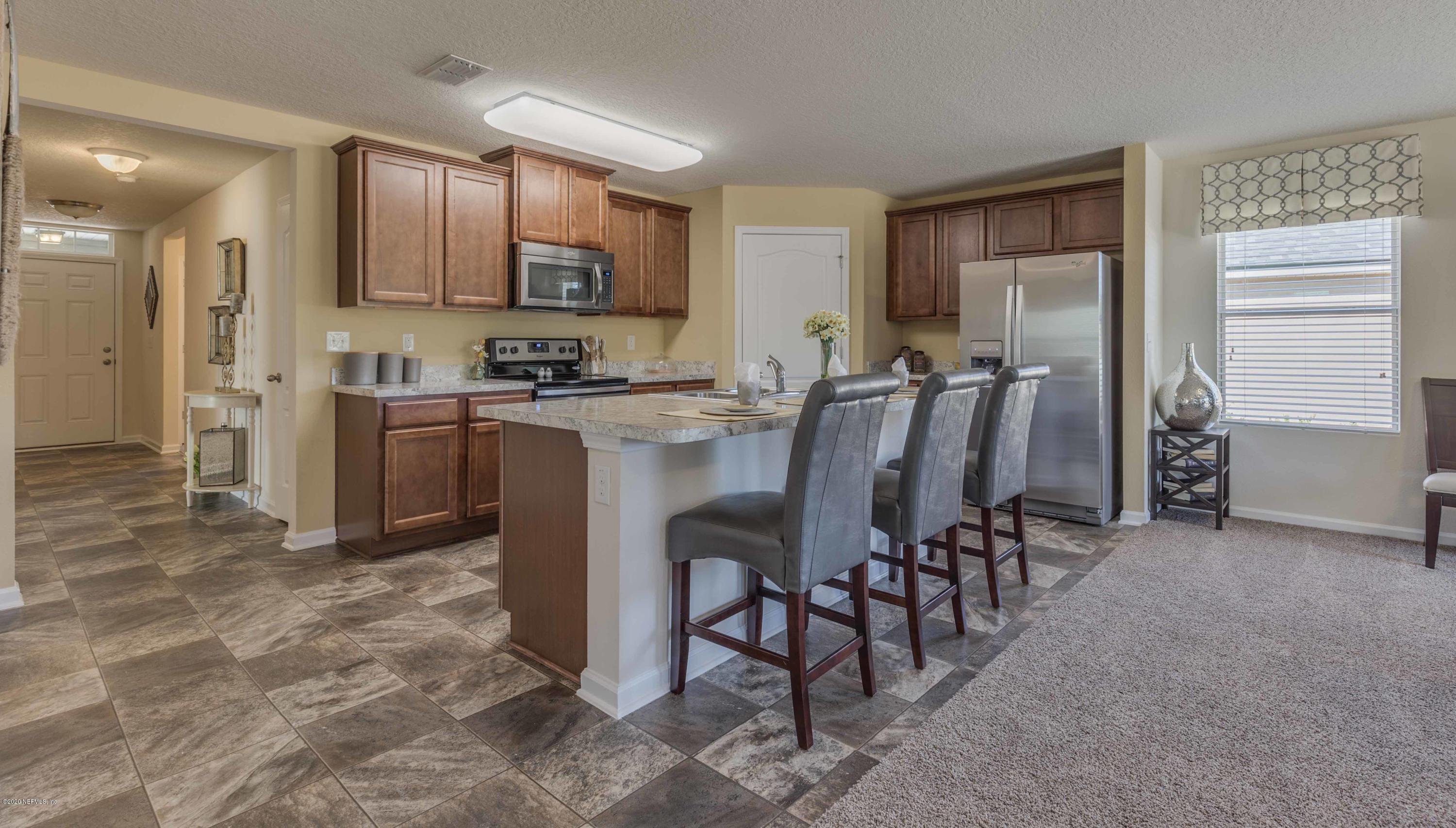 3820 Great Falls Loop Middleburg, FL 32068 - Photo 15 of 36 a kitchen with stainless steel appliances a table chairs refrigerator and microwave