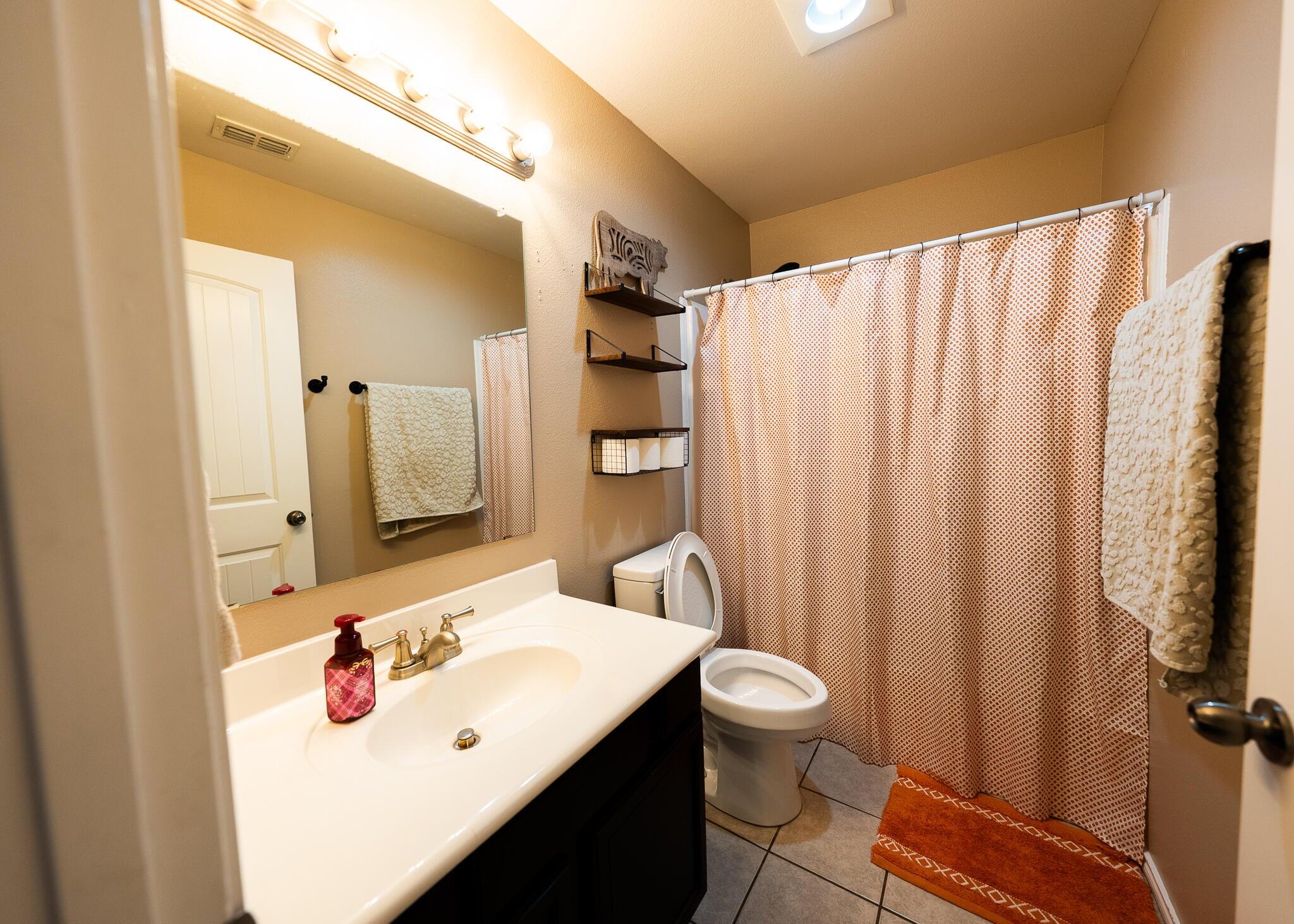 9104 Quincy Avenue Lubbock, TX 79424 - Photo 11 of 15 a bathroom with a sink a toilet and shower curtain