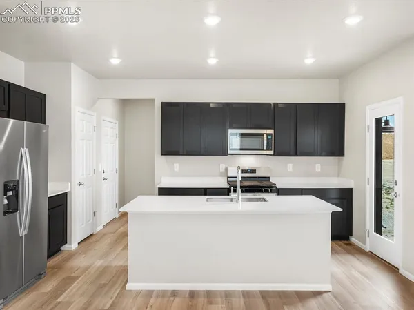 a kitchen with stainless steel appliances a refrigerator a sink a stove a microwave and wooden floor