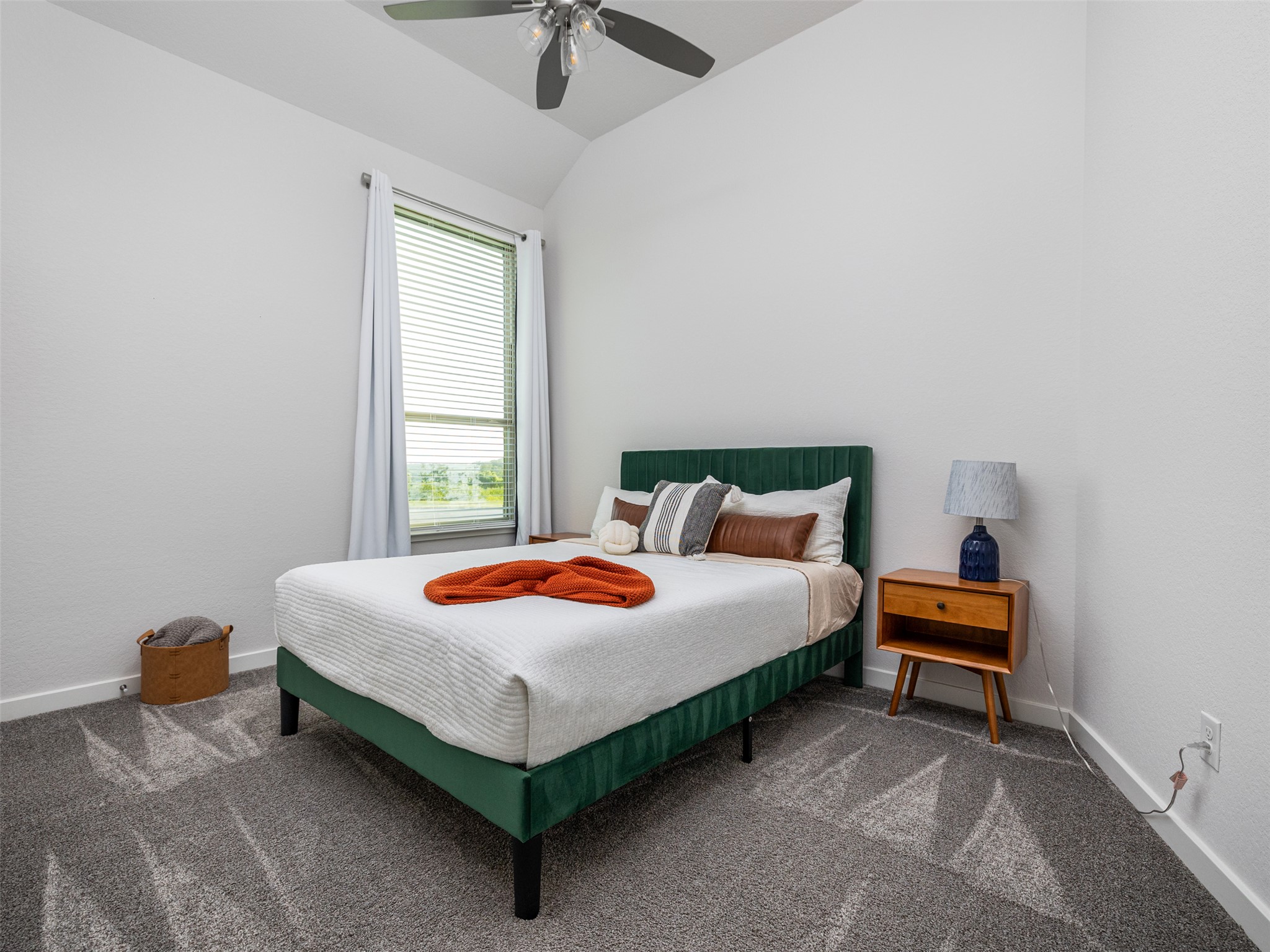 606 Spinnaker Loop Kyle, TX 78640 - Photo 18 of 37 A well-lit bedroom with textured carpeting and a sloped ceiling features an ample window offering distant views.