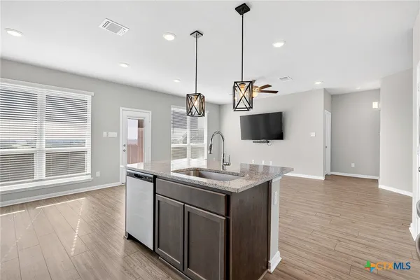 a view of a kitchen with kitchen island a sink and wooden floor