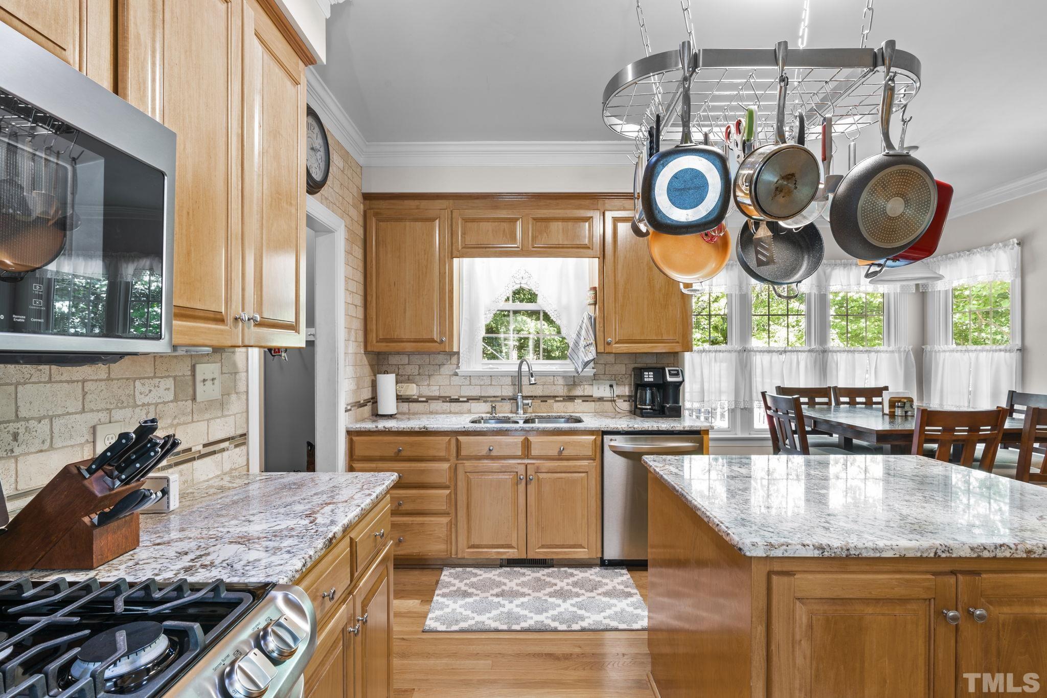 7705 Tylerton Drive Raleigh, NC 27613 - Photo 11 of 35 a kitchen with stainless steel appliances granite countertop a stove a sink and a wooden cabinets