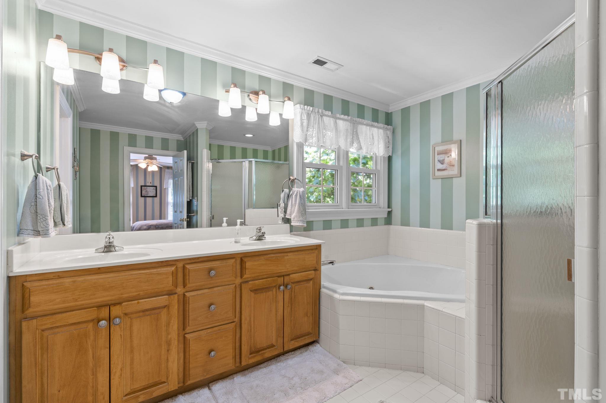 7705 Tylerton Drive Raleigh, NC 27613 - Photo 16 of 35 a bathroom with a tub sink and mirror