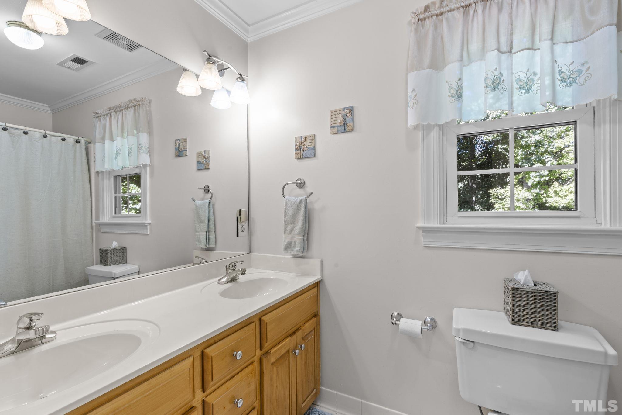 7705 Tylerton Drive Raleigh, NC 27613 - Photo 18 of 35 a bathroom with a double vanity sink toilet and a mirror