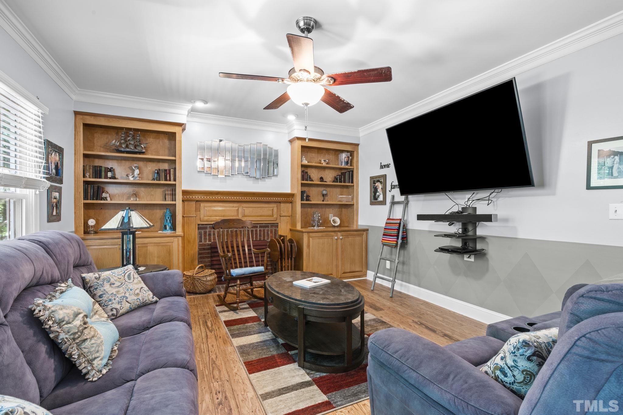 7705 Tylerton Drive Raleigh, NC 27613 - Photo 6 of 35 a living room with furniture a flat screen tv and a floor to ceiling window