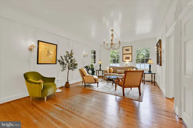 a living room with furniture a chandelier and wooden floor