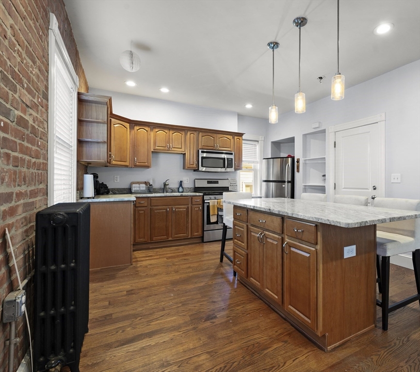493 Broadway, Unit 2 Somerville, MA 02145 - Photo 1 of 24 a kitchen with stainless steel appliances granite countertop wooden cabinets a refrigerator a sink a stove and a wooden floors