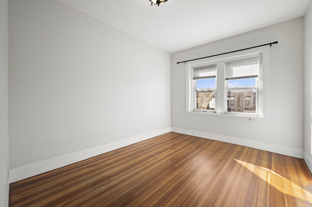 493 Broadway, Unit 2 Somerville, MA 02145 - Photo 11 of 24 a view of an empty room with wooden floor and a window
