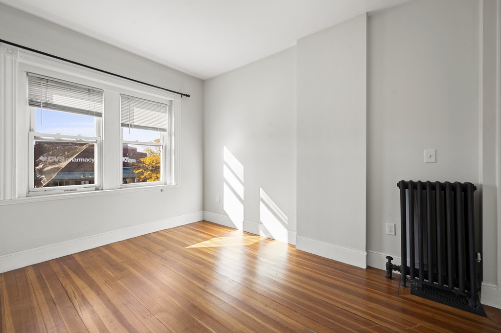 493 Broadway, Unit 2 Somerville, MA 02145 - Photo 12 of 24 a view of an empty room with wooden floor and a window