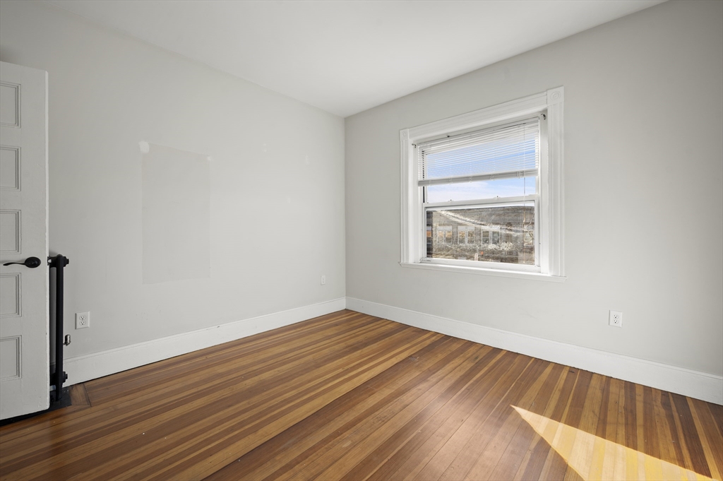 493 Broadway, Unit 2 Somerville, MA 02145 - Photo 14 of 24 an empty room with wooden floor and windows