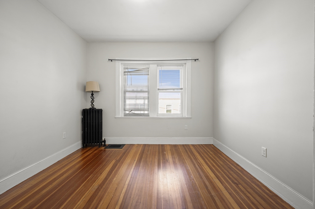 493 Broadway, Unit 2 Somerville, MA 02145 - Photo 19 of 24 an empty room with wooden floor and windows