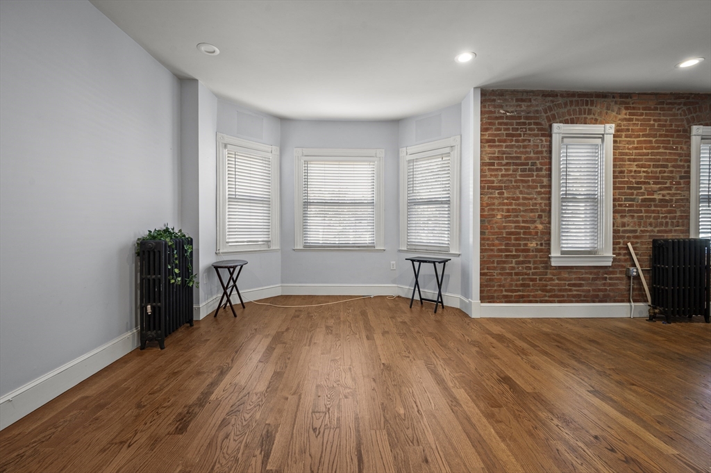 493 Broadway, Unit 2 Somerville, MA 02145 - Photo 3 of 24 a view of an empty room with wooden floor and a window