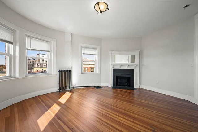 a view of empty room with wooden floor and fireplace