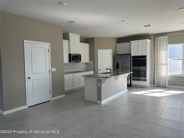 a large white kitchen with a sink a counter top space stainless steel appliances and cabinets