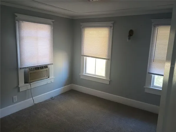 an empty room with a fireplace and windows