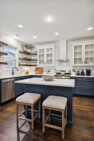a kitchen with stainless steel appliances granite countertop a stove and a white wooden cabinets