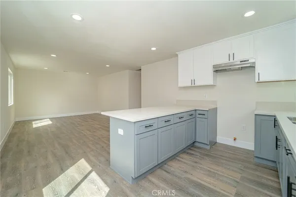 a kitchen that has a lot of cabinets in it and wooden floors