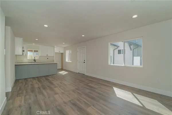 a view of an empty room with kitchen and window