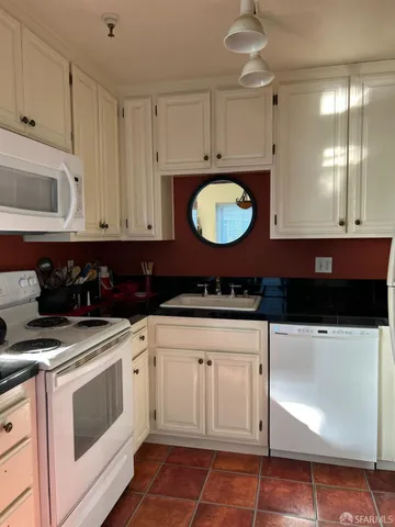 a kitchen with a sink dishwasher and white cabinets
