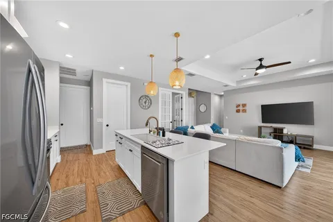 a large living room with stainless steel appliances granite countertop couches a flat screen tv with kitchen view