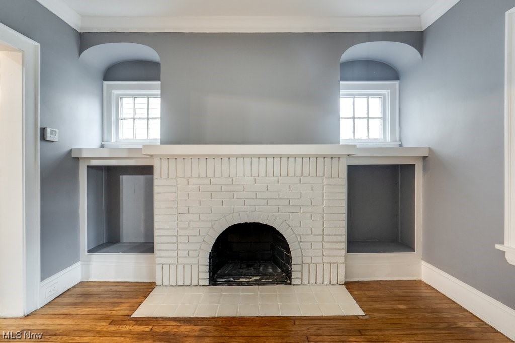3393 Cedarbrook Road Cleveland, OH 44118 - Photo 8 of 43 Unfurnished living room with wood-type flooring, a brick fireplace, and crown molding