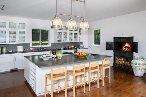 a kitchen with stainless steel appliances granite countertop a stove a refrigerator a sink dishwasher a dining table and chairs with wooden floor