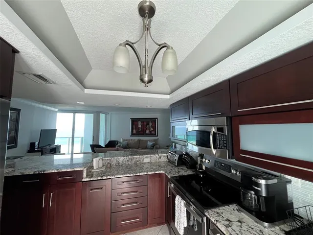 a living room with furniture a flat screen tv and kitchen view