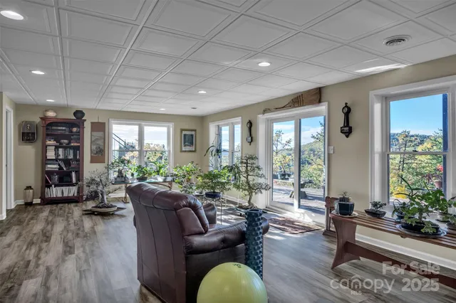 a living room with furniture potted plant floor to ceiling windows and a flat screen tv
