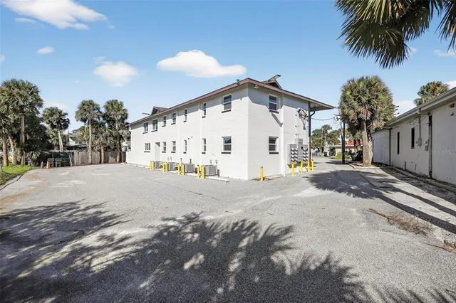 a view of a white house with a yard and parking space