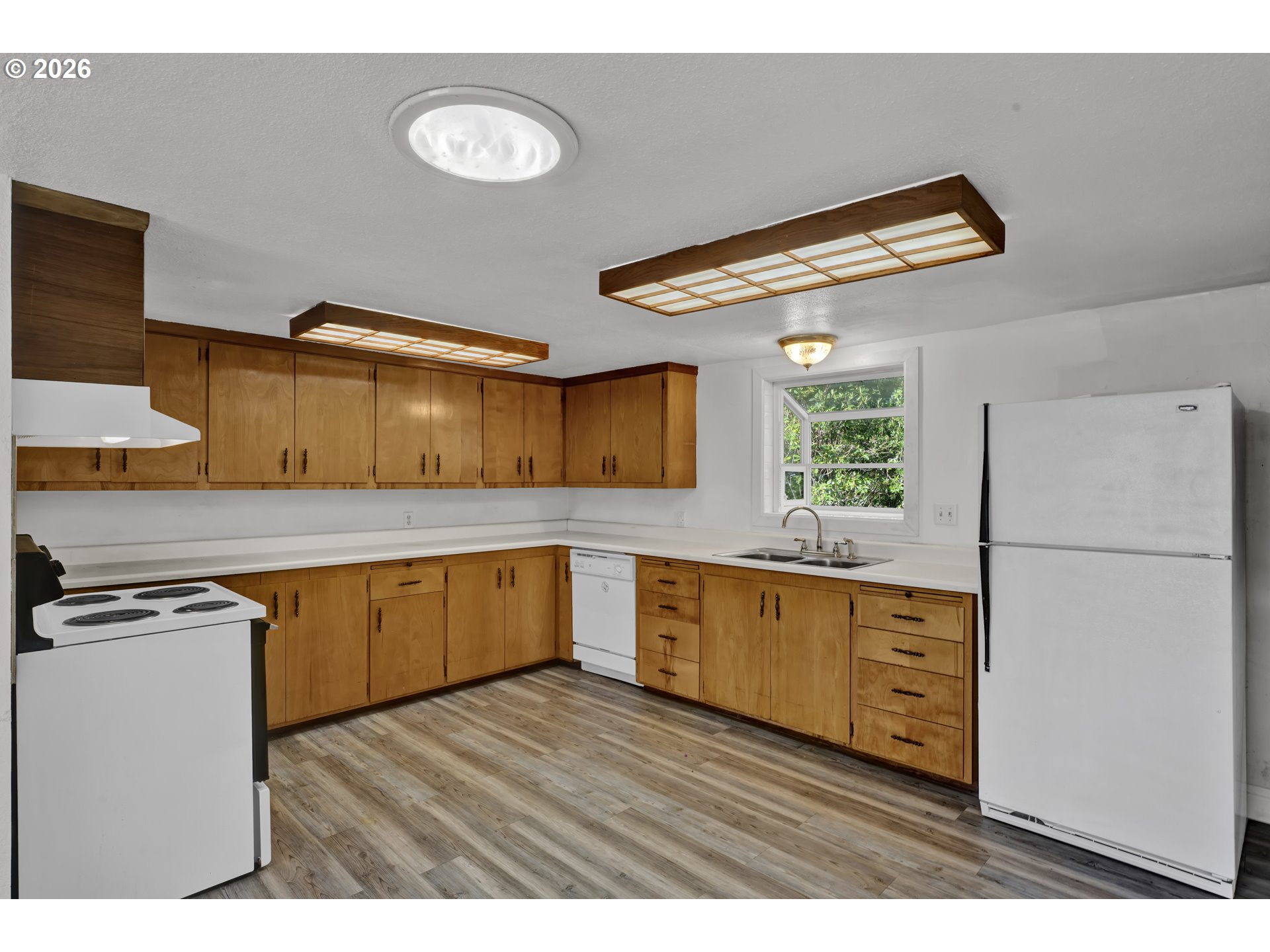 777 Rhododendron Drive Florence, OR 97439 - Photo 19 of 41 a kitchen with granite countertop a refrigerator a stove a sink dishwasher and wooden cabinets with wooden floor