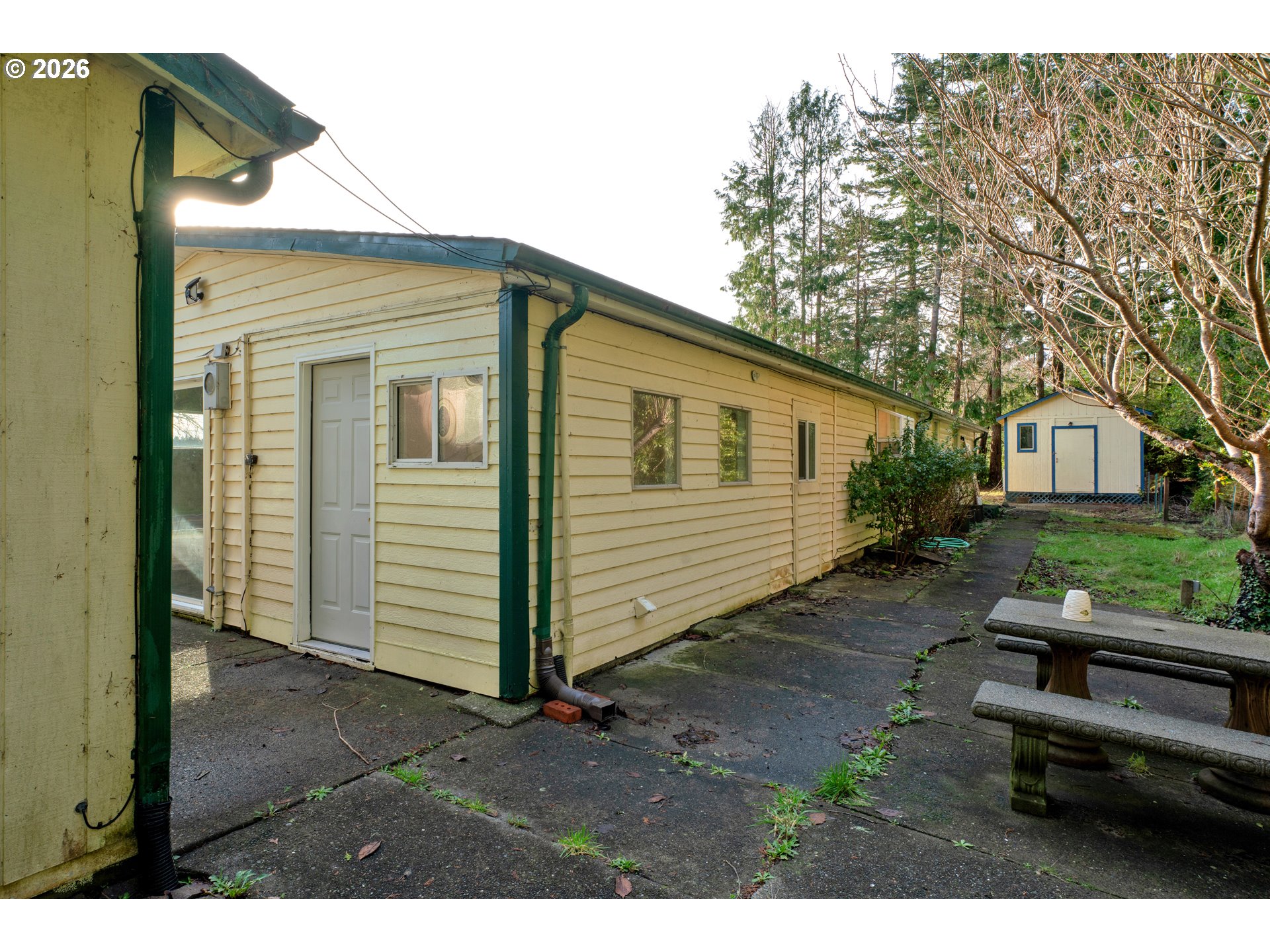 777 Rhododendron Drive Florence, OR 97439 - Photo 37 of 41 a backyard of a house with wooden fence and large trees