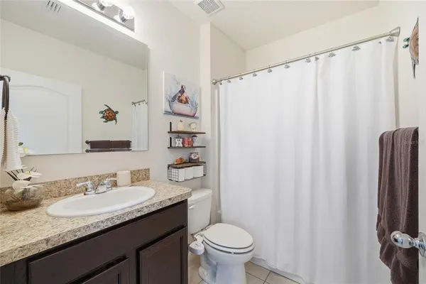 a bathroom with a granite countertop sink a toilet and a shower