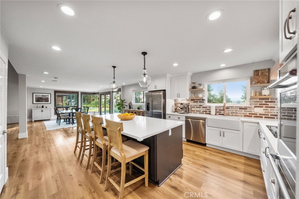 40221 Paseo Sereno Temecula, CA 92591 - Photo 12 of 45 a kitchen with stainless steel appliances granite countertop a stove top oven a sink dishwasher a dining table and chairs with wooden floor